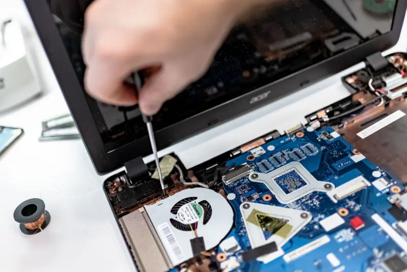 Kapağı açılmış laptopun anakartında tornavidayla onarım